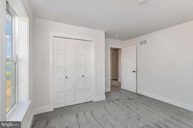 unfurnished bedroom featuring light colored carpet and a closet