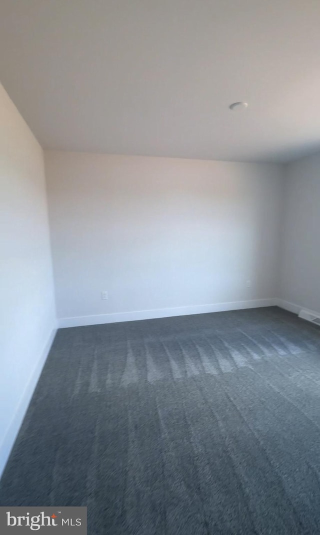 unfurnished room with dark carpet