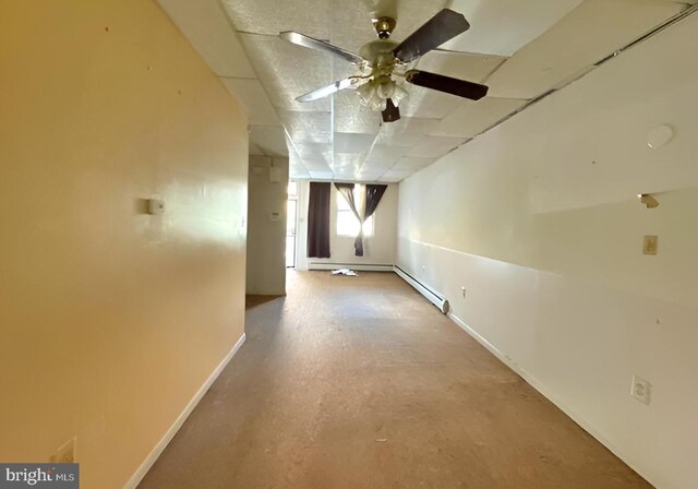 unfurnished room featuring a baseboard heating unit, ceiling fan, and a paneled ceiling