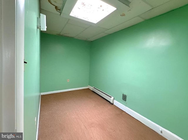 unfurnished room featuring carpet flooring, a drop ceiling, and a baseboard heating unit