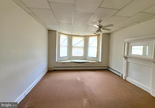 carpeted empty room with ceiling fan, a paneled ceiling, and a baseboard radiator