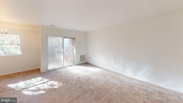 carpeted empty room with a chandelier