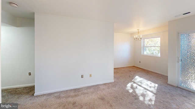 carpeted spare room with a notable chandelier