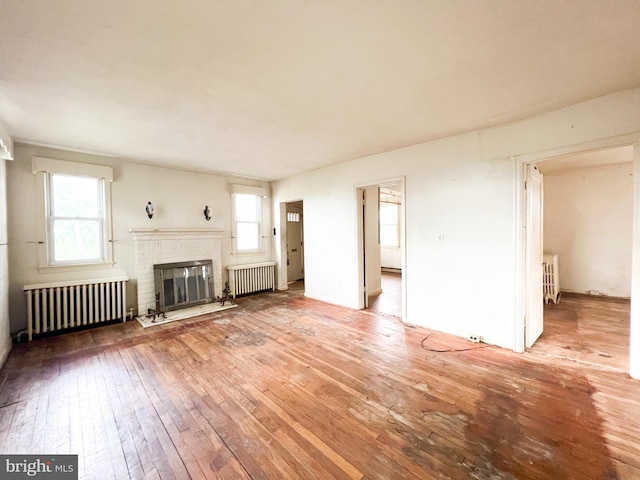 unfurnished living room with wood-type flooring, plenty of natural light, and radiator