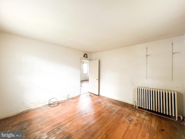 empty room featuring radiator and hardwood / wood-style floors