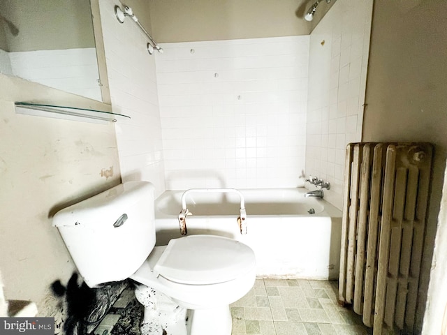 bathroom with tiled shower / bath, radiator, and toilet