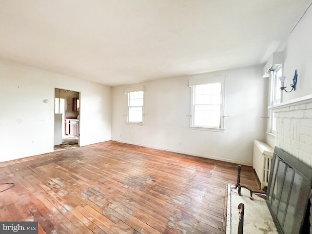 unfurnished living room featuring hardwood / wood-style floors, a fireplace, and radiator