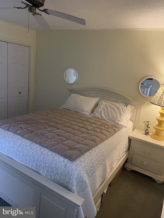 carpeted bedroom with a textured ceiling, ceiling fan, and a closet