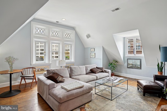 living room with lofted ceiling, wood finished floors, visible vents, and baseboards