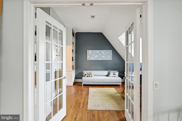 bedroom with lofted ceiling, french doors, visible vents, and wood finished floors