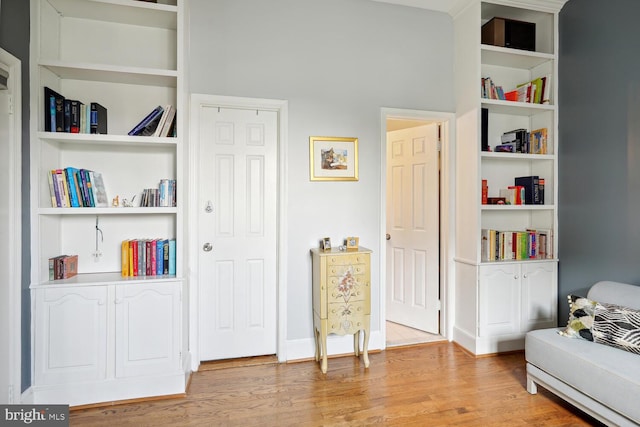 living area with built in features, light wood-type flooring, and baseboards