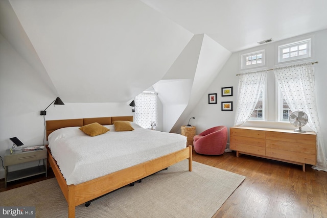 bedroom with lofted ceiling, hardwood / wood-style floors, and visible vents