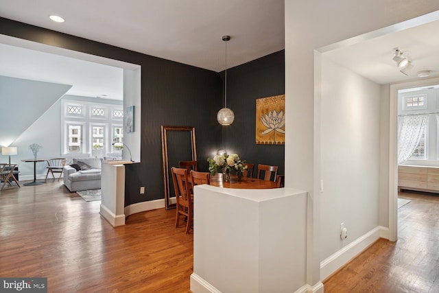 interior space featuring an accent wall, baseboards, and wood finished floors