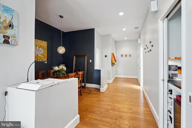 corridor with light wood-type flooring, baseboards, and recessed lighting