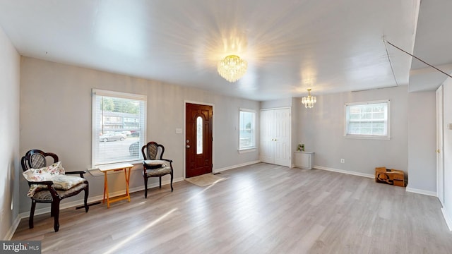 entrance foyer with a chandelier, a healthy amount of sunlight, and light hardwood / wood-style flooring