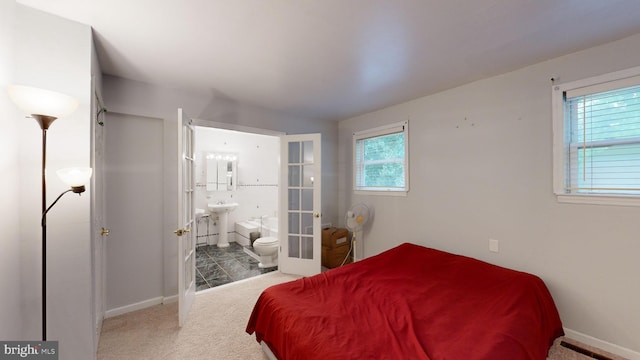 bedroom with french doors, connected bathroom, carpet flooring, and sink