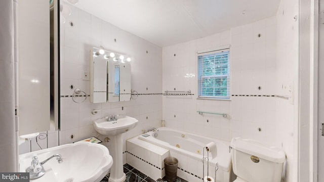 bathroom with sink, tile walls, toilet, and tiled tub