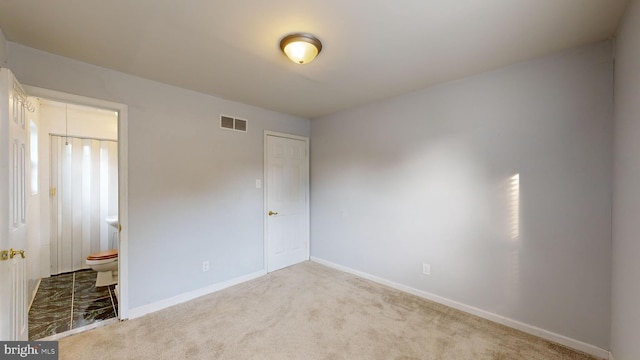 unfurnished bedroom featuring light carpet and ensuite bathroom