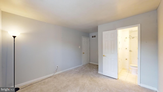 unfurnished bedroom featuring light carpet and connected bathroom