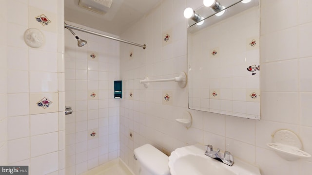 bathroom with sink, tile walls, a tile shower, toilet, and tasteful backsplash