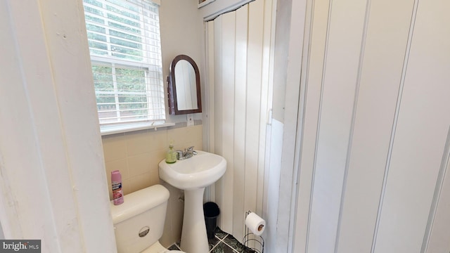 bathroom featuring toilet and tile walls