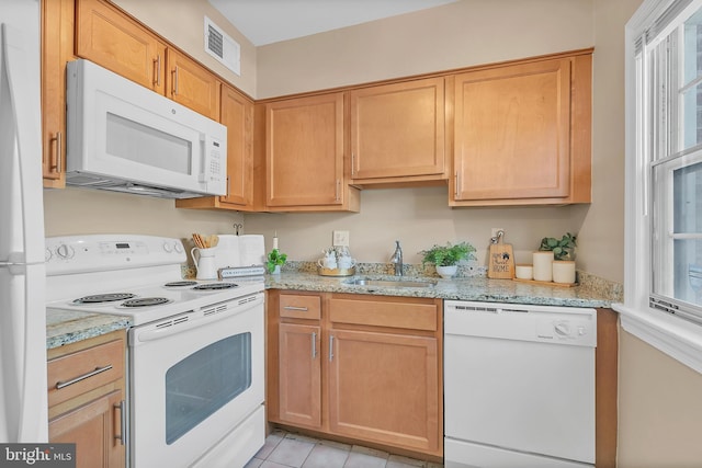 kitchen featuring light stone countertops, sink, and white appliances