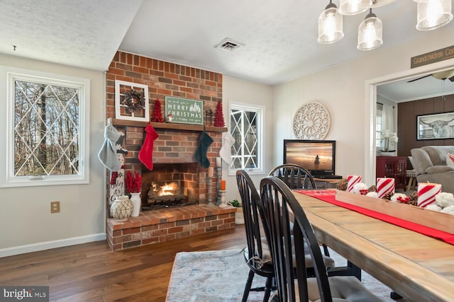 dining space featuring dark hardwood / wood-style flooring, a brick fireplace, and a textured ceiling