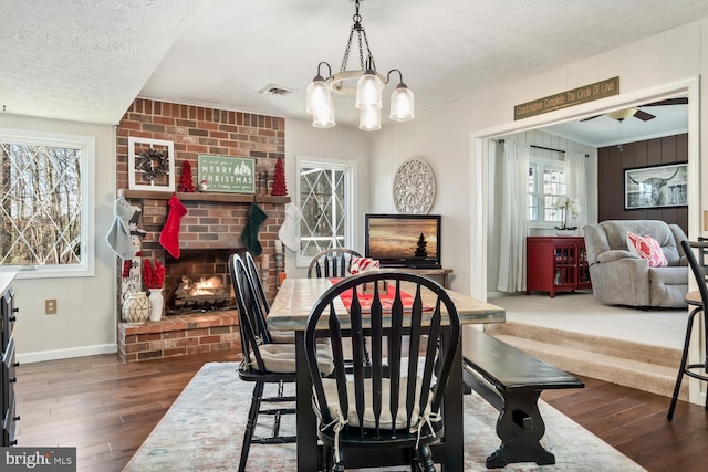 dining area featuring a brick fireplace, dark hardwood / wood-style floors, and a textured ceiling