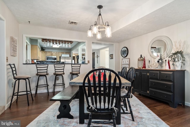 dining room featuring dark wood-type flooring, a notable chandelier, and a textured ceiling