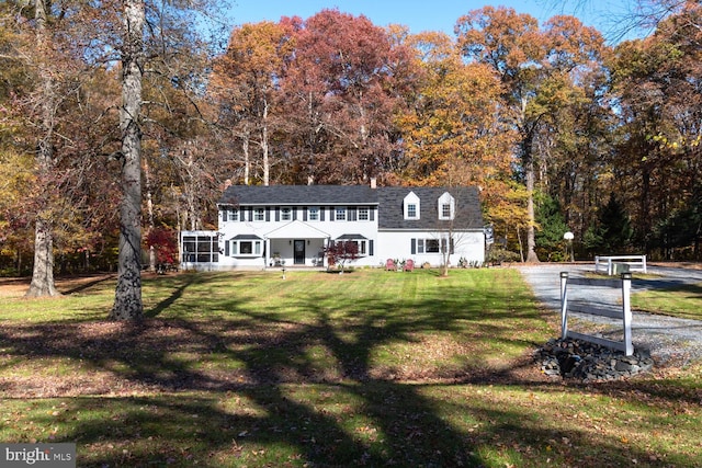 view of front of house with a front yard and a sunroom