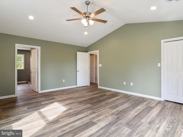 unfurnished bedroom featuring lofted ceiling, baseboards, wood finished floors, and recessed lighting