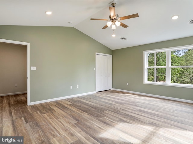 interior space with light wood-type flooring, visible vents, vaulted ceiling, and baseboards