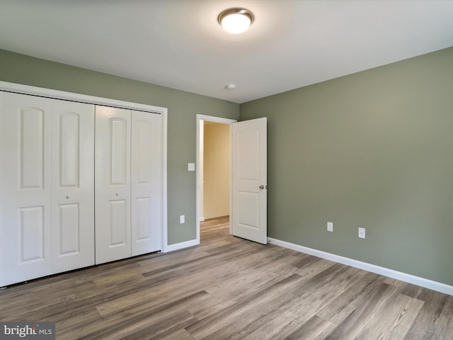 unfurnished bedroom with light wood-style flooring, baseboards, and a closet