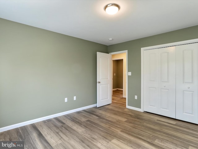 unfurnished bedroom with a closet, baseboards, and wood finished floors