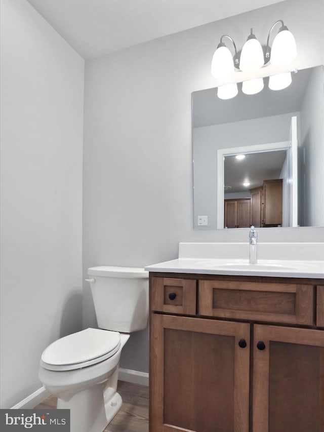 bathroom with toilet, baseboards, wood finished floors, and vanity