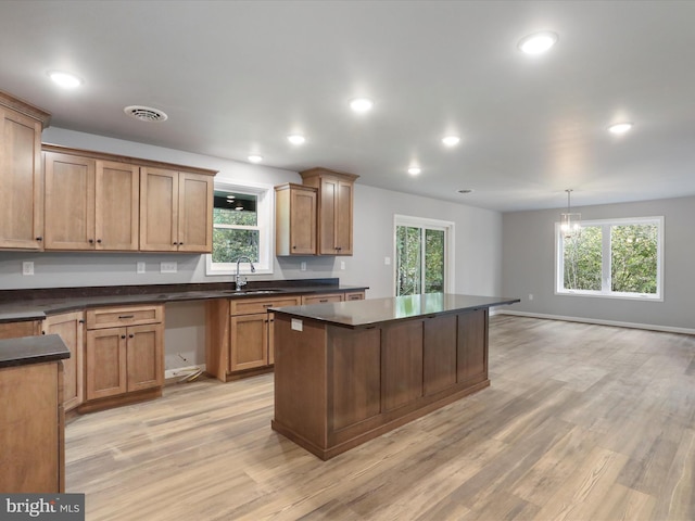 kitchen with dark countertops, light wood-type flooring, pendant lighting, and a wealth of natural light