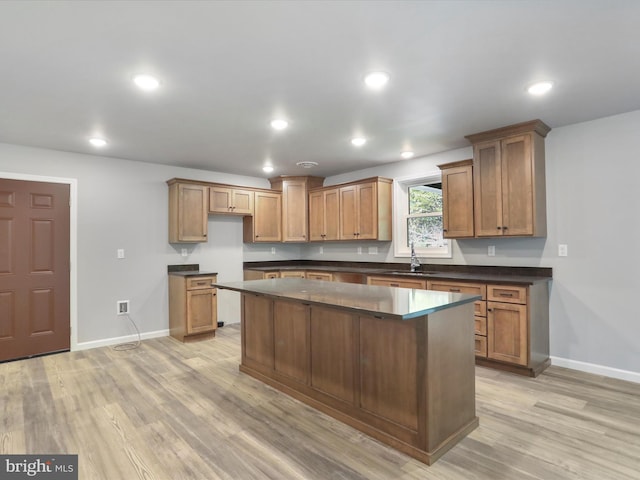 kitchen with recessed lighting, a kitchen island, a sink, light wood-type flooring, and dark countertops