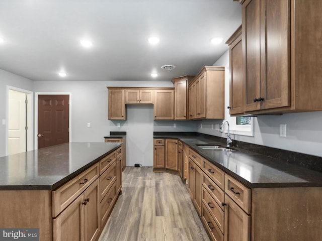 kitchen with visible vents, brown cabinets, light wood-type flooring, a sink, and recessed lighting