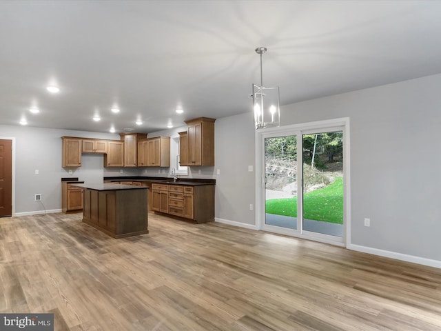 kitchen with dark countertops, recessed lighting, hanging light fixtures, brown cabinetry, and light wood-type flooring