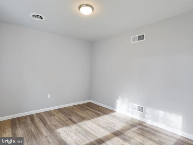 empty room with light wood-type flooring, baseboards, and visible vents