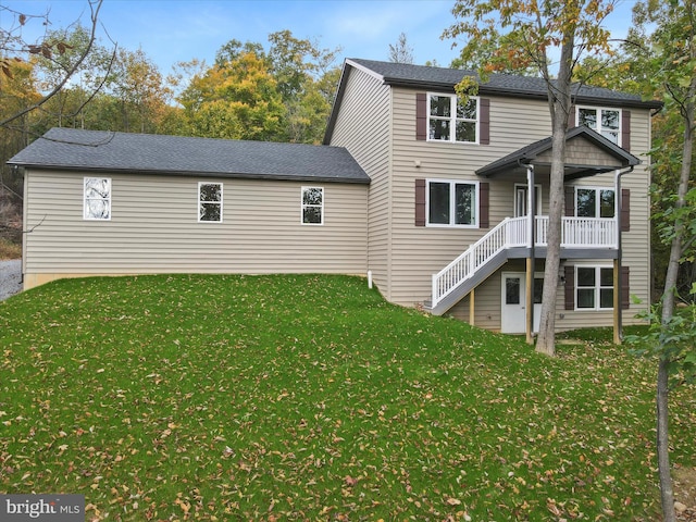 rear view of property featuring a lawn and stairway