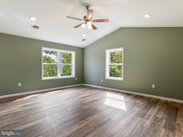 unfurnished room with lofted ceiling, baseboards, visible vents, and dark wood-style flooring