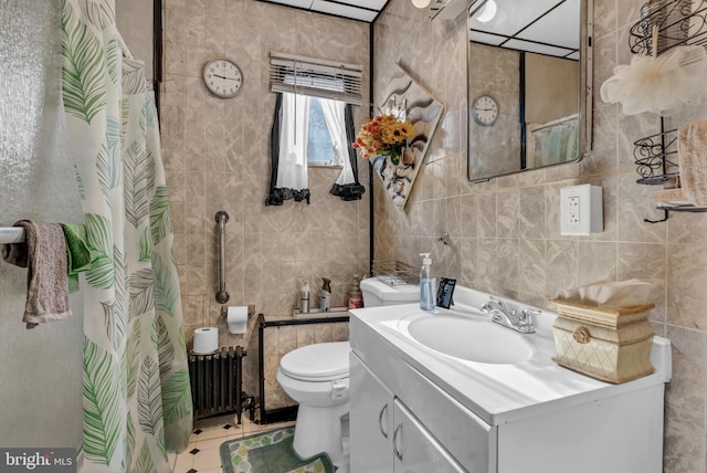 bathroom with radiator heating unit, toilet, vanity, tile walls, and tile patterned floors