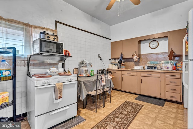 kitchen with tasteful backsplash, white gas range, ceiling fan, tile walls, and light brown cabinets