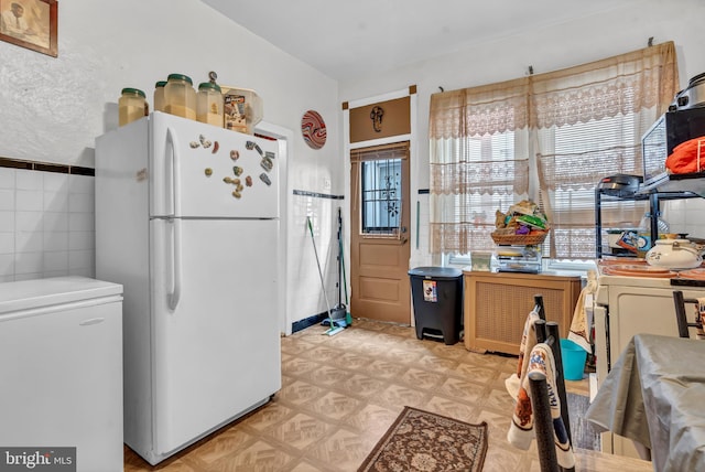 kitchen featuring white fridge, tile walls, a healthy amount of sunlight, and refrigerator