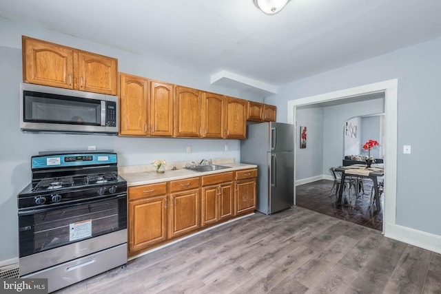 kitchen with stainless steel appliances, hardwood / wood-style flooring, and sink