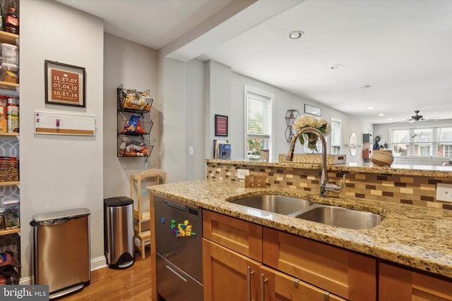 kitchen featuring light stone counters, tasteful backsplash, sink, and ceiling fan