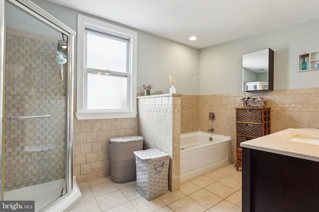 bathroom with a wealth of natural light, tile patterned flooring, and tile walls