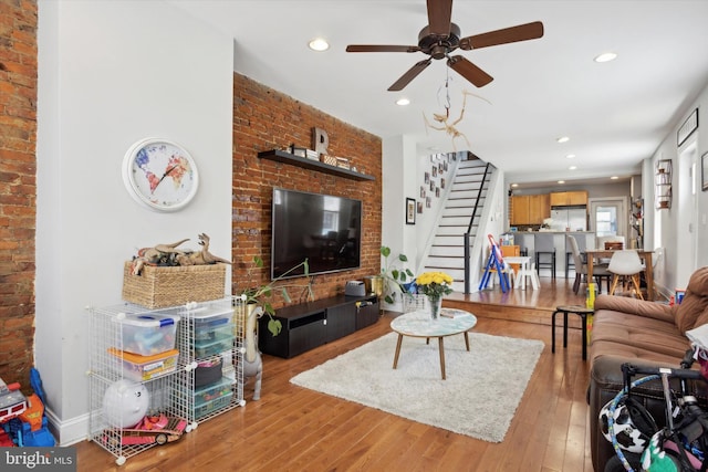 living room featuring light hardwood / wood-style floors, brick wall, and ceiling fan