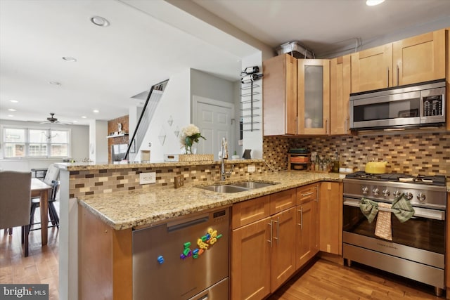 kitchen featuring appliances with stainless steel finishes, kitchen peninsula, and light wood-type flooring